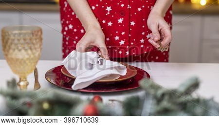 Female Hands Close Up Set The Table For Christmas, Decorating It With White Napkin, Plates And Wineg