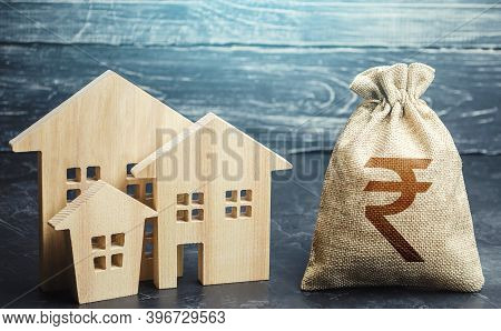 Indian Rupee Money Bag And Figurines Of Residential Buildings. Property Tax. Municipal Budgeting. Fi