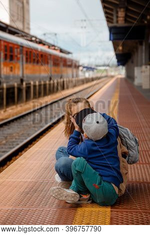 Woman With Son On The Platform Near The Train. Girl With A Preschool Boy Sitting At The Train Statio