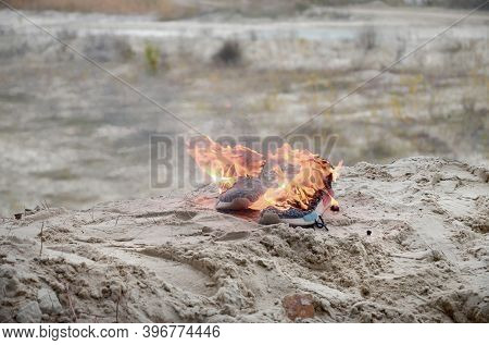 Burning Sports Sneakers Or Gym Shoes On Fire Stand On Sandy Beach Coast. Athlete Burned Out. Physica