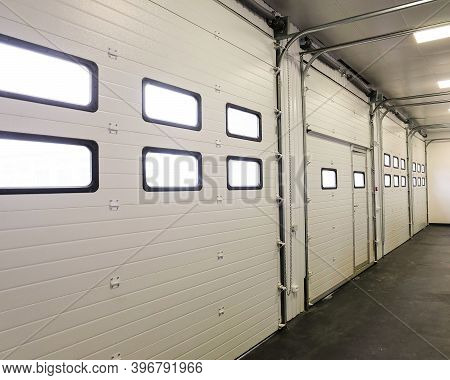Row Of Overhead Sectional Doors In A Multi-seat Car Garage. Inside View.