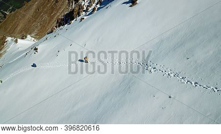 A Group Of Climbers Climb To The Top Of The Peak. Dangerous, Steep Slope. Avalanche-prone Area. Moun