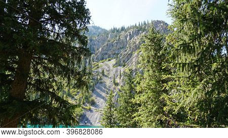 Mountain Lake Kolsay With Floating Boats. View Of Green Hills, Fir Trees, Grass And Water. Boats Wit