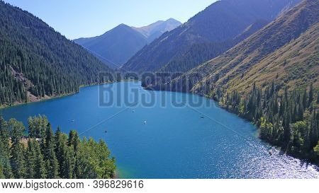 Kolsay Lake Among Green Hills And Mountains. The Mountain Lake Is Surrounded By Green Forest, Tall C