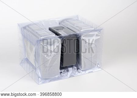 Two Computer Speakers In Transparent Plastic Bag On White Background. In The Middle Between The Spea