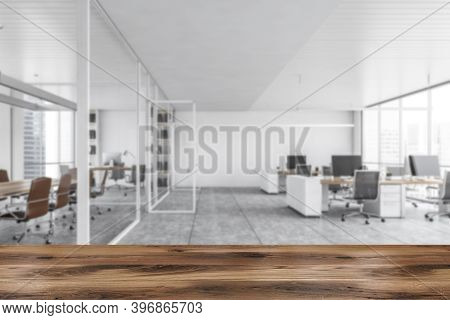 White Office Open Space Room, Wooden Desk On Foreground. Blurred Background With Tables And Computer