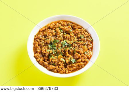 Close Up View Of Keema Curry In Bowl Over Yellow Background With Copy Space. Indian And Pakistani St