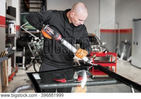 Glazier Applying Rubber Sealing To Windshield In Garage, Close Up. High Quality Photo