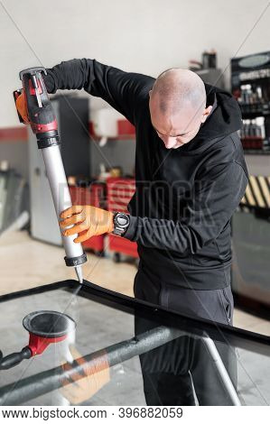 Glazier Applying Rubber Sealing To Windshield In Garage, Close Up. High Quality Photo