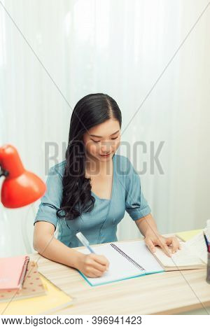 Teen Girl Preparing For Test Exam With Laptop And Book Writing Essay Coursework In Notebook Studying