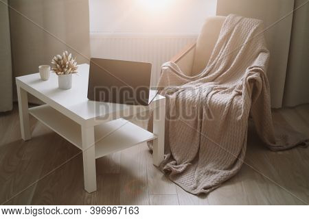 Laptop Computer And Coffee On Table And Cozy Chair With Plaid. Remote Work At Home Office. Cozy Livi