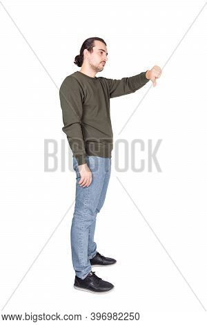 Side View Full Length  Portrait Of Displeased Young Man Showing Thumb Down, Negative Gesture And Bad
