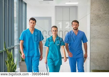 Three Doctors Walking Together In The Hospital Corridor