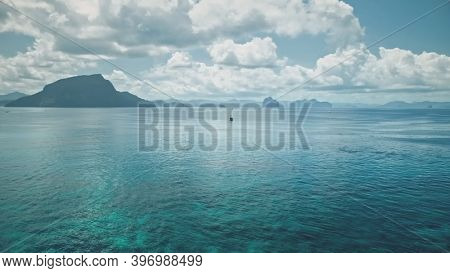 Serene blue water with mountainous islets of El Nido, Philippines, Asia. Panorama seascape with tropic islands aerial view. Lonely sail yacht at marine scape. Cinematic soft light drone shot