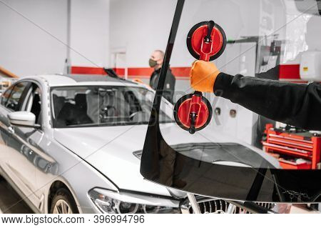 Automobile Technician Worker Replacing Windscreen Or Windshield Of A Car In Auto Service Station Gar