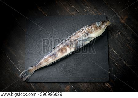 Frozen Mackerel Icefish On A Black Stone Background. High Quality Photo