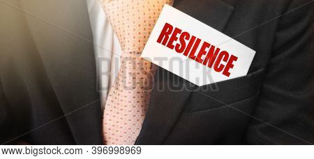 Businessman Putting A Card With Text Resilence In The Pocket. Business Environment Concept
