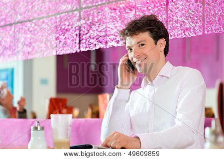 Young man in a cafe or ice cream parlor using his phone, maybe he is single or waiting for someone
