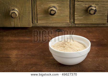 baobab fruit powder in a small bowl with a rustic drawer cabinet