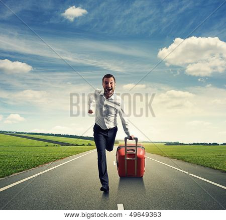 happy businessman running with suitcase on the road