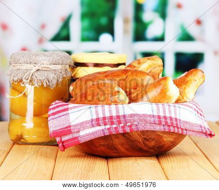 Fresh baked pasties with fruit jam, on wooden table, on bright background