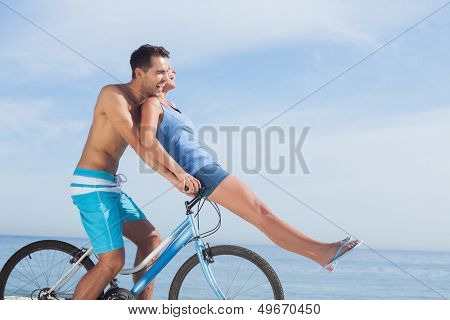 Man giving girlfriend a lift on his crossbar of bike on the beach