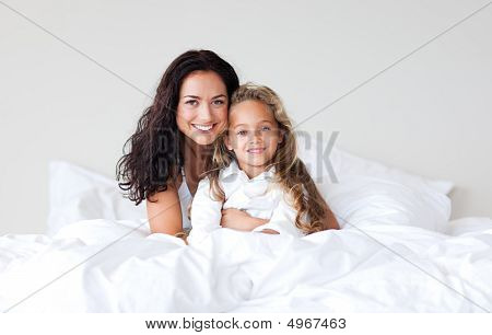 Mutter und Tochter auf dem Bett Lächeln in die Kamera