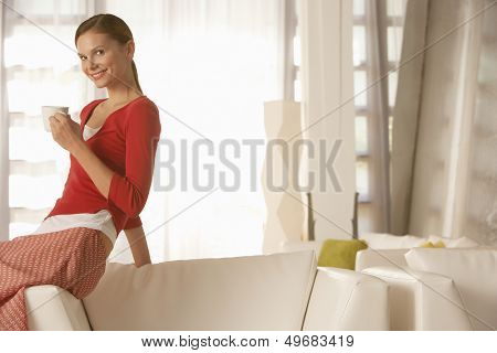 Portrait of happy young businesswoman holding coffee cup in office lobby