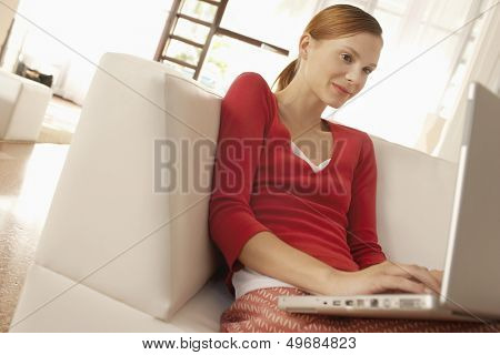 Young businesswoman using laptop while sitting on chair in office lobby