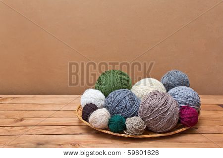Multicolored Yarn  Balls In A Straw Basket On A Wooden Table
