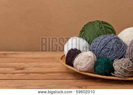 Multicolored Yarn Balls In A Straw Basket On A Wooden Table