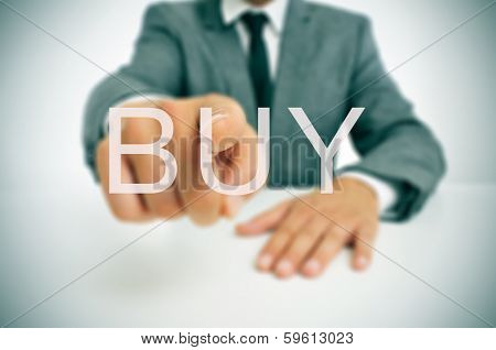 businessman sitting in a desk pointing the word buy written in the foreground