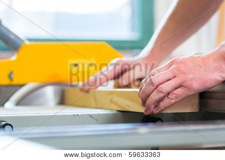 Carpenter working on an electric buzz saw and cutting some boards in carpentry