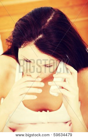 Top view face closeup of a beautiful young woman, being stressed during talking on the phone, holging her fingers close to her lips.