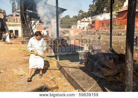 KATHMANDU, NEPAL - DEC 3, 2013: Unidentified local people during the cremation ceremony along the holy Bagmati River in Bhasmeshvar Ghat at Pashupatinath temple in Kathmandu.