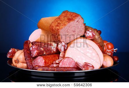 Lot of different sausages on salver on dark colorful background