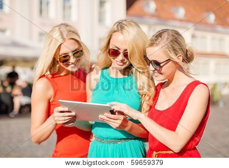holidays and tourism concept - beautiful blonde girls toursits looking into tablet pc in the city
