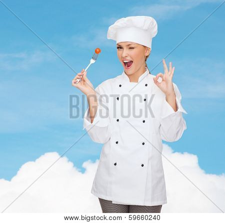 cooking and food concept - smiling female chef, cook or baker with fork and tomato showing ok sign