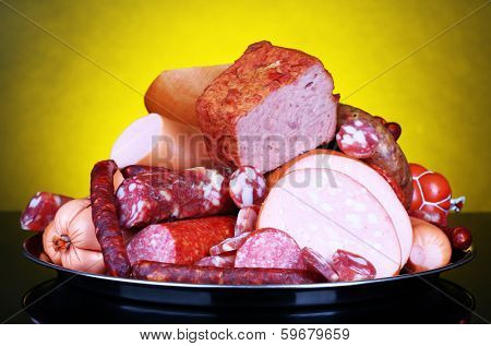 Lot of different sausages on salver on dark colorful background
