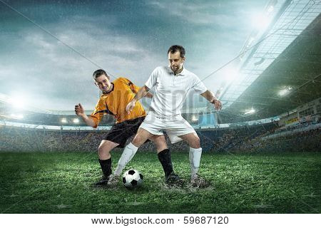 Two football players with ball in action outdoors.