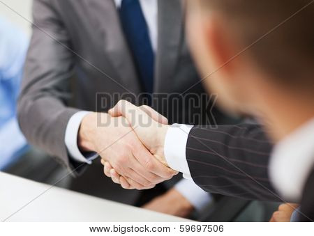 businesss and office concept - two businessmen shaking hands in office