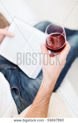 leisure, drinks, education and lifestyle concept - close up of male hand holdind book and glass of red wine