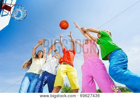 Kids playing basketball with a ball up in sky