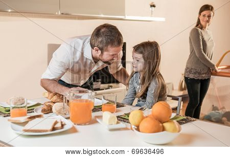 Father having breakfast with his little girl, mother in the background on playpen