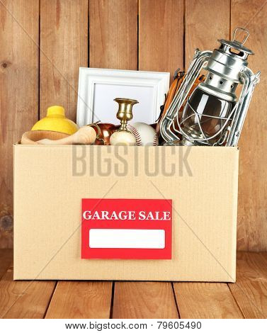 Box of unwanted stuff ready for a garage sale on wooden background