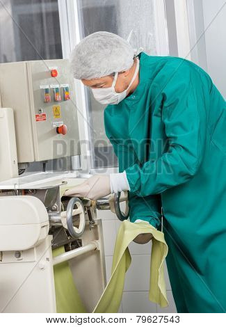 Chef in protective workwear using spaghetti pasta machine at commercial kitchen