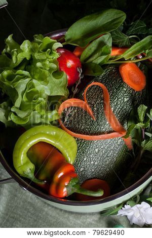 raw vegetables in a saucepan and heart carrots, vegan