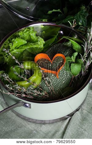raw vegetables in a saucepan and heart carrots, vegan