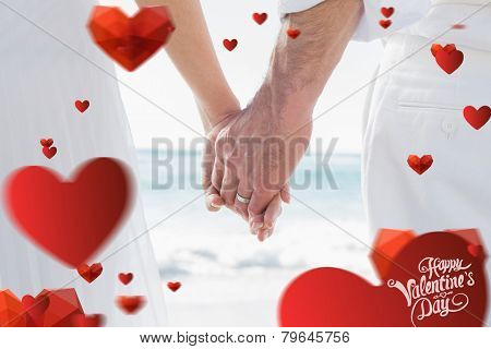 Bride and groom holding hands close up against cute valentines message