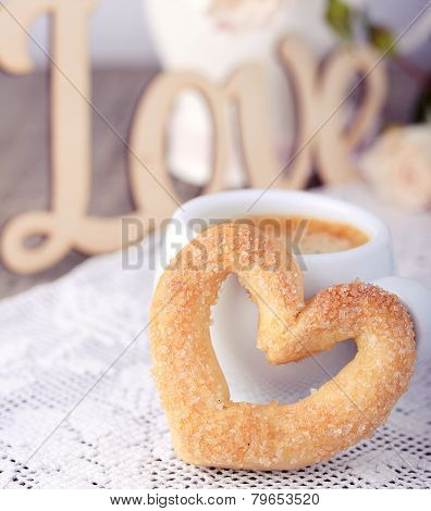 Heart-shaped biscuit on wooden background.